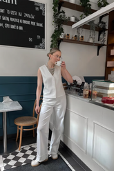 a lady wears a white suit vest with white pants